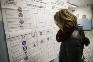 Un'elettrice davanti all'elenco dei partiti e dei candidati