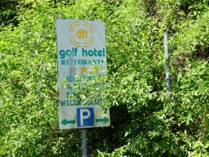 Il cartello, all'esterno del Golf Hotel, che spunta tra le sterpaglie