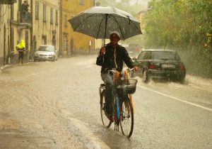 Un venditore di ombrelli affronta con la bicicletta la forte pioggia nel corso della giornata di lunedì 29 ottobre (foto Massimo Pasquali)