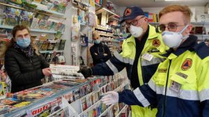 Un'edicolante consegna i giornali ai volontari della Protezione Civile