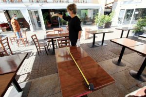 Un ristoratore controlla la distanza dei tavoli