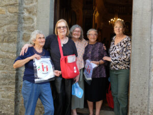Roma Musetti sulla porta della chiesa parrocchiale di Bosco con Rita e Gemma (con i gagliardetti dell’Associazione), due delle protagoniste del film di Alicia Cano Menoni