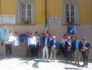 Foto di gruppo dei partecipanti alla cerimonia, sotto alla targa che ricorda il Sottotenente Lorenzo Quartieri.